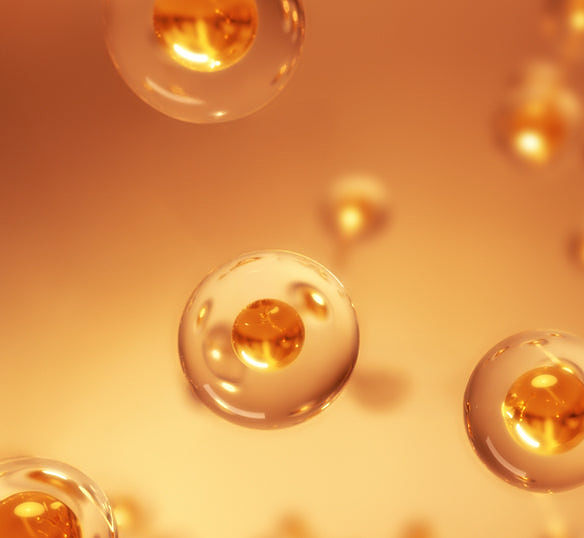 A stylised 3D rendering of multiple translucent, spherical cells floating against a golden-orange background. Each cell contains a smaller, golden sphere at its core, suggesting an active ingredient.