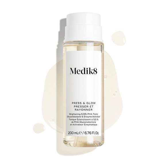 Flacon Medik8 Press & Glow – placé sur un fond blanc épuré avec des gouttes de liquide translucides et une petite flaque, mettant en valeur sa texture aqueuse. Le texte identifie le produit comme un tonique exfoliant quotidien PHA de 200 mL avec activateur enzymatique.-1