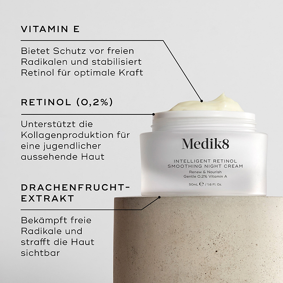 Nahaufnahme der Intelligent Retinol Smoothing Night Cream. Zu sehen ist ein weißer Tiegel mit Creme und Etiketten mit Hinweisen auf die Inhaltsstoffe. Der Hintergrund ist hell und strukturiert. Textfelder heben Vitamin E, Retinol (0,2 %) und Drachenfruchtextrakt hervor.-hover-2