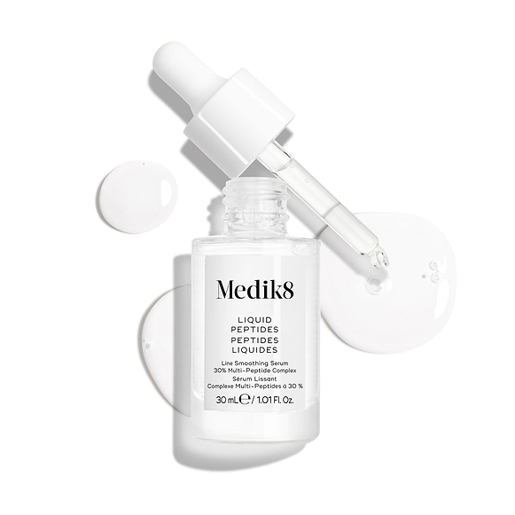 Číra sklenená kvapkacia fľaštička séra Liquid Peptides je zobrazená s odstránenou pipetou položenou vedľa nej a kvapôčkami séra, ktoré znázorňujú jeho textúru.-17
