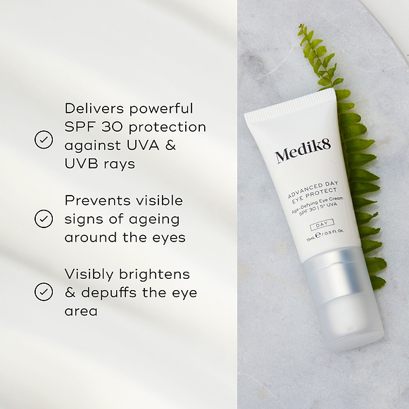 Advanced Day Eye Protect tube lies on a marble surface next to a green fern leaf. Text highlights its SPF 30 protection, prevention of visible ageing signs, and its ability to brighten and depuff the eye area.-hover-11
