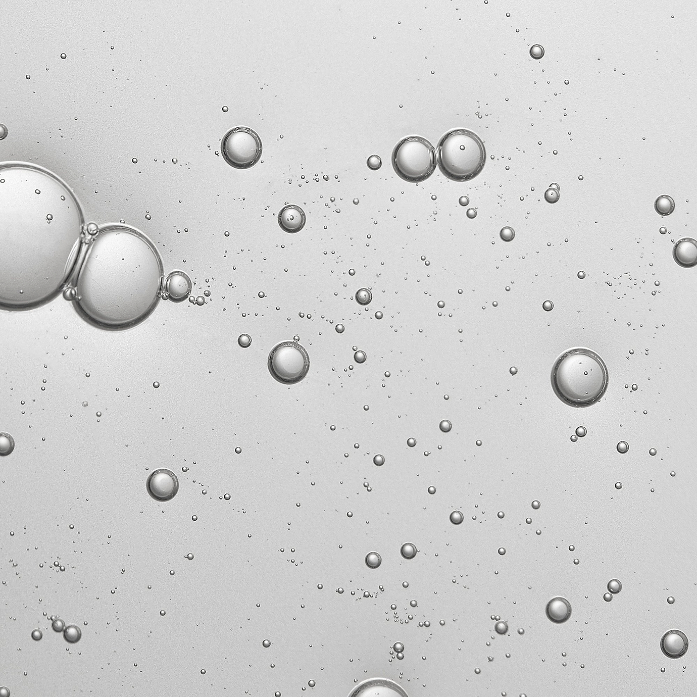A close-up of clear bubbles suspended in a transparent liquid against a light grey background, symbolising a peptide formulation.