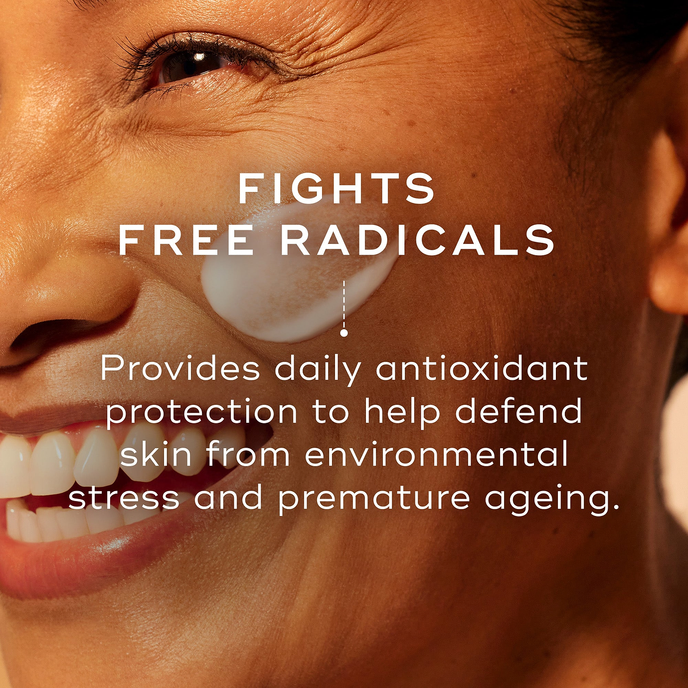 Close-up of a smiling person’s face on a warm orange background. Text reads: ‘Fights Free Radicals.’ Supporting text reads: ‘Provides daily antioxidant protection to help defend skin from environmental stress and premature ageing.’