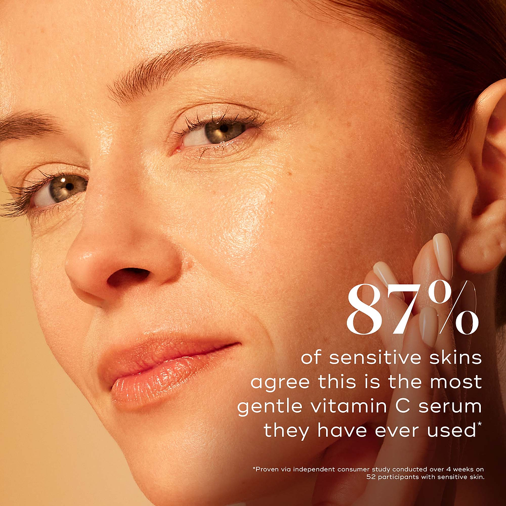 Close-up of a model with glowing skin gently touching her cheek against a warm gradient background. Text highlights that 87% of sensitive skins agree this is the most gentle vitamin C serum they have ever used, proven via an independent consumer study.