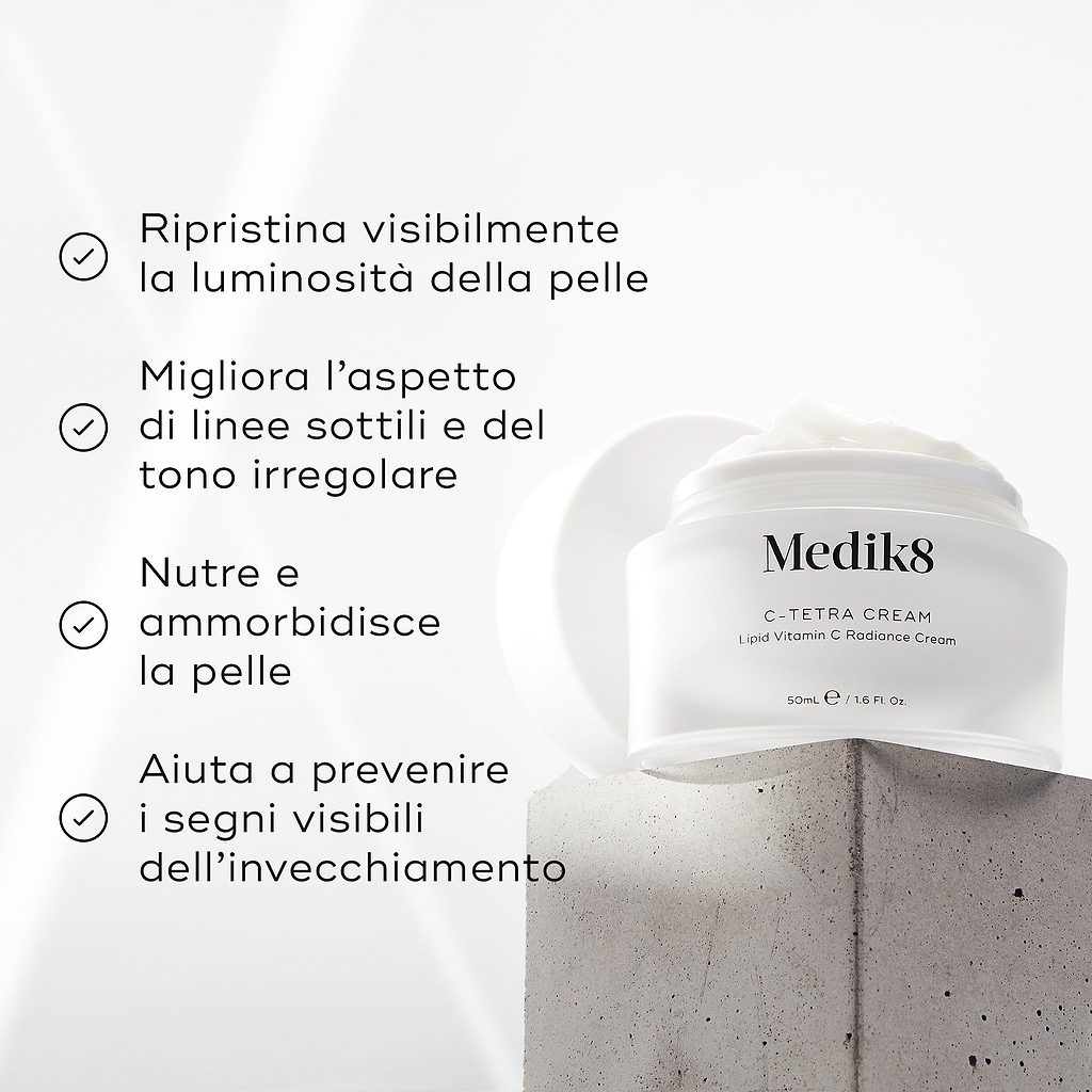 Barattolo di crema Medik8 C-Tetra esposto su un blocco di pietra grigia su uno sfondo bianco con raggi di luce morbida. L’immagine mostra quattro affermazioni con segno di spunta: ripristina visibilmente la radiosità della pelle, migliora l’aspetto delle linee sottili e del tono cutaneo irregolare, nutre e ammorbidisce la pelle, aiuta a prevenire i segni visibili dell’invecchiamento.