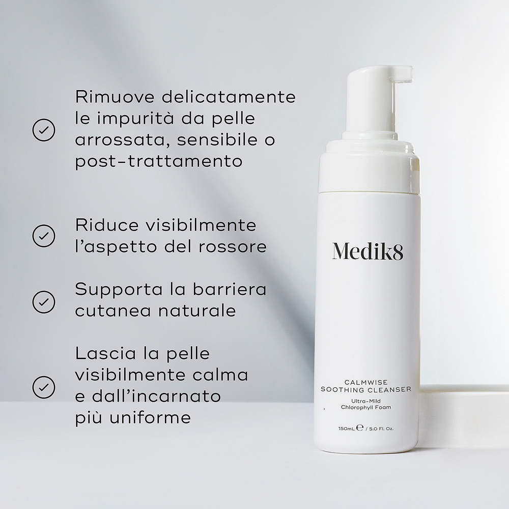 Il flacone di Medik8 Calmwise Soothing Cleanser si trova su un blocco bianco contro uno sfondo grigio chiaro. Il testo in italiano descrive i benefici della schiuma ultra-delicata alla clorofilla, tra cui la rimozione delicata delle impurità dalla pelle arrossata, sensibile o post-trattamento, la riduzione visibile dell'aspetto del rossore, il supporto alla barriera cutanea naturale e il lasciare la pelle visibilmente calma con un incarnato più uniforme.