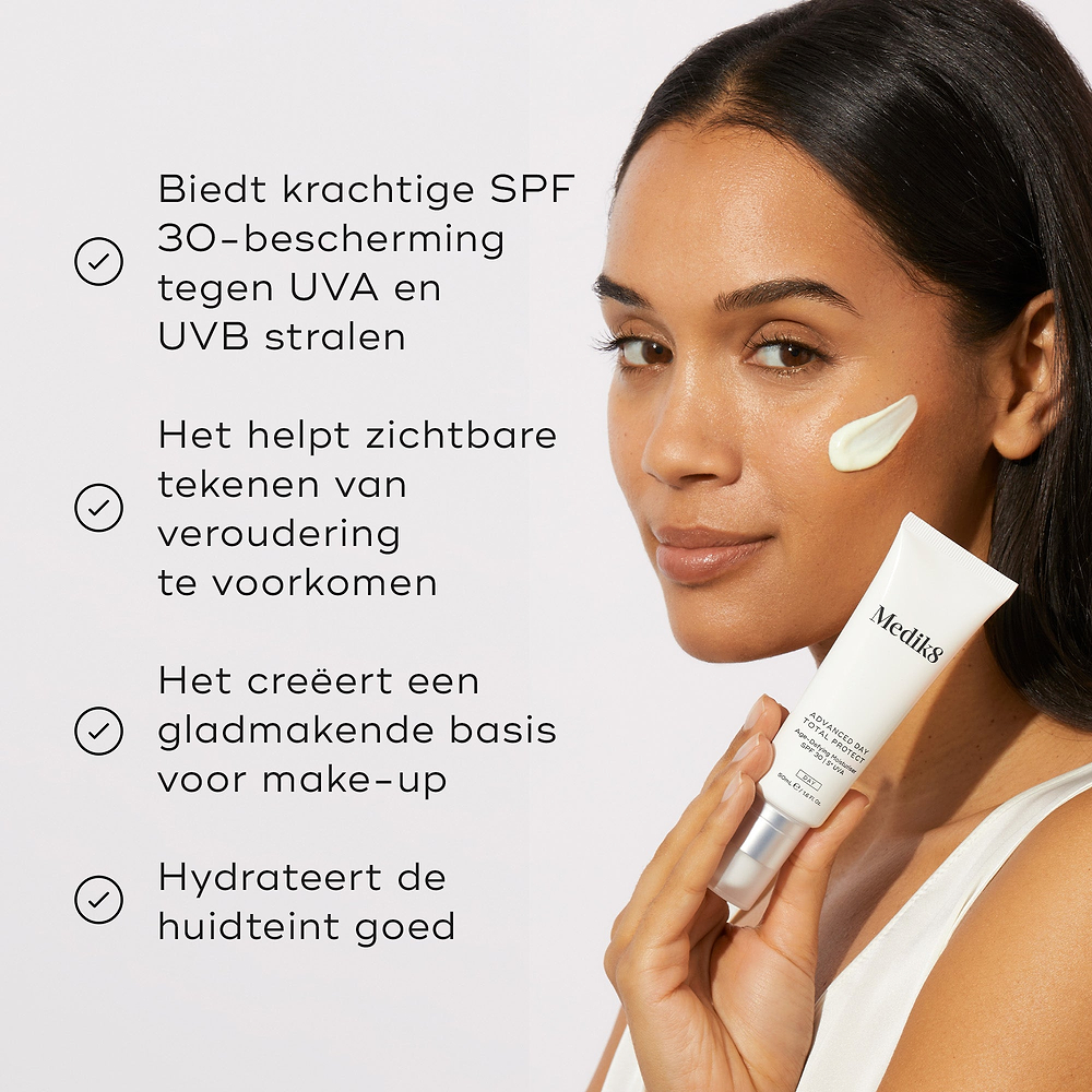 Een vrouw brengt Medik8 Advanced Day Total Protect aan op haar wang. Vier bulletpoints lichten de voordelen van het product uit: krachtige SPF 30 UVA- en UVB-bescherming, het helpen voorkomen van zichtbare tekenen van huidveroudering, het creëren van een gladde basis voor make-up en intensieve hydratatie.