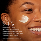 Close-up zijaanzicht van een glimlachend model met een veeg crème op haar wang. Vetgedrukte tekst vermeldt dat 94% aangeeft dat Medik8 Daily Radiance Vitamin C meer aanvoelt als een moisturizer dan als een zonnebrandcrème.