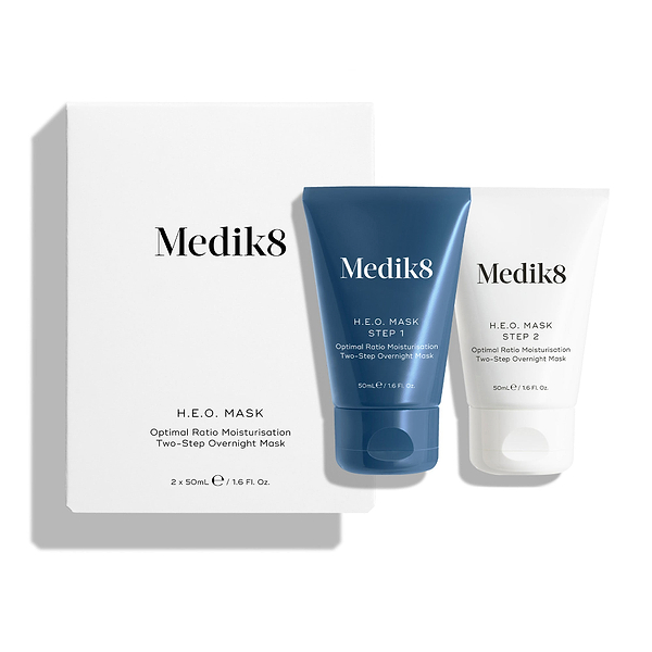 Een witte productverpakking voor het H.E.O.-masker staat naast twee tubes van het masker.