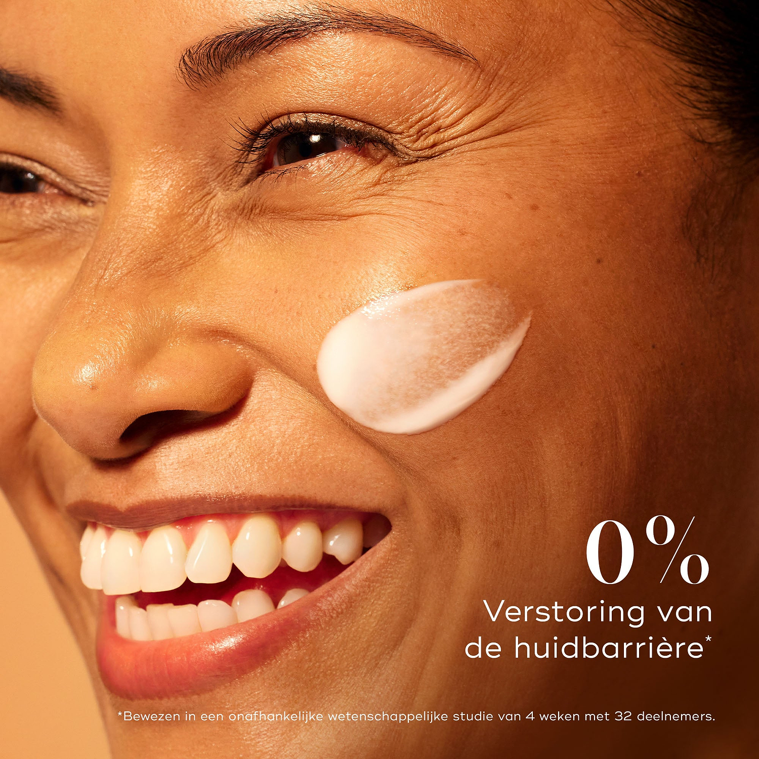Lachende vrouw met een stralende huid en een veeg Medik8 C-Tetra Advanced serum op haar wang, die 0% barrièreverstoring benadrukt voor een milde maar effectieve werking voor een helderdere huid.