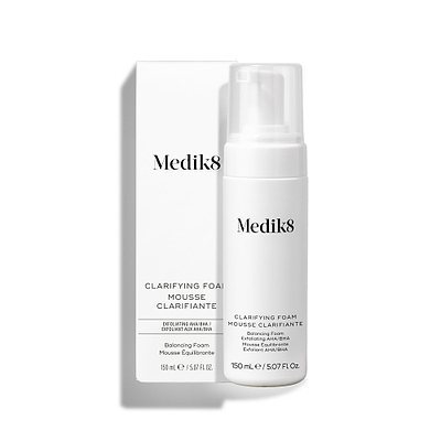 De Medik8 Clarifying Foam-pompfles staat naast de bijpassende witte buitenverpakking tegen een strakke witte achtergrond. De tekst op zowel de fles als de verpakking vermeldt dat het gaat om een 150 ml Refreshing AHA/BHA Blemish Cleanser.