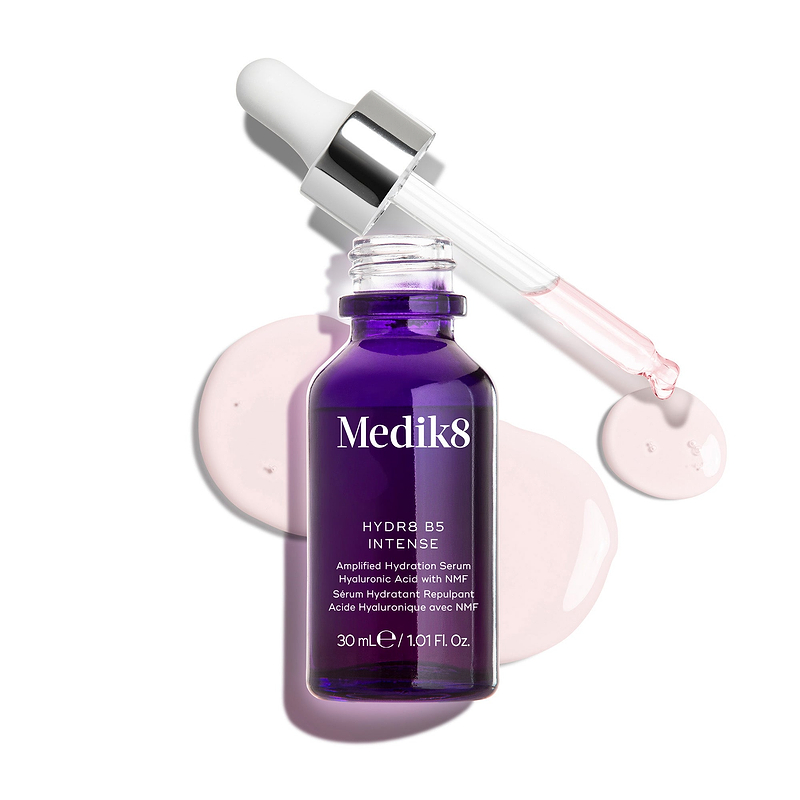 Een diep paarse glazen pipetflacon van Medik8 Hydr8 B5 Intense, weergegeven met een geopende pipet boven lichtroze serumdruppels tegen een strakke witte achtergrond. De tekst benadrukt de formule als Hyaluronic Acid with NMF (Natural Moisturising Factors) to Replenish & Boost in een inhoud van 30 ml.