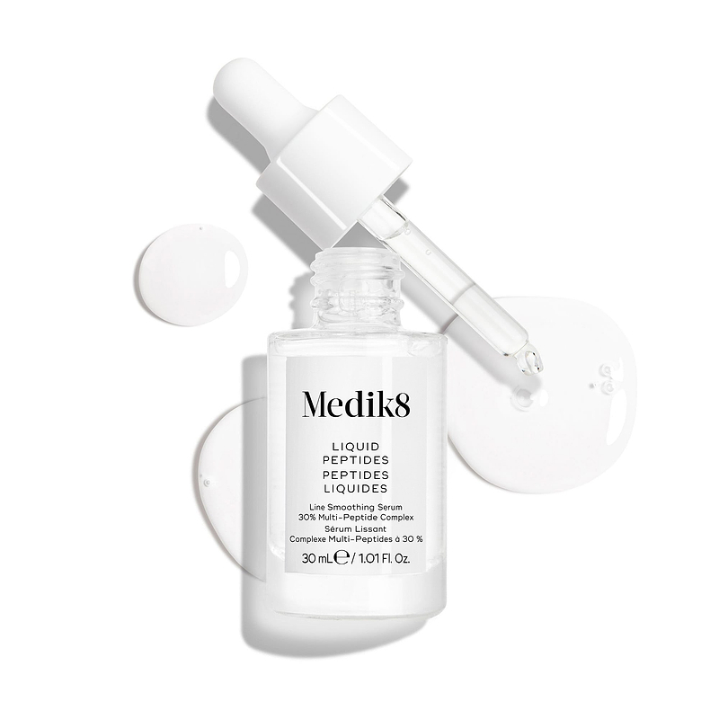 Een heldere glazen pipetflacon van Liquid Peptides-serum wordt weergegeven met de pipet verwijderd en ernaast geplaatst, samen met serumdruppels die de textuur van het serum laten zien.