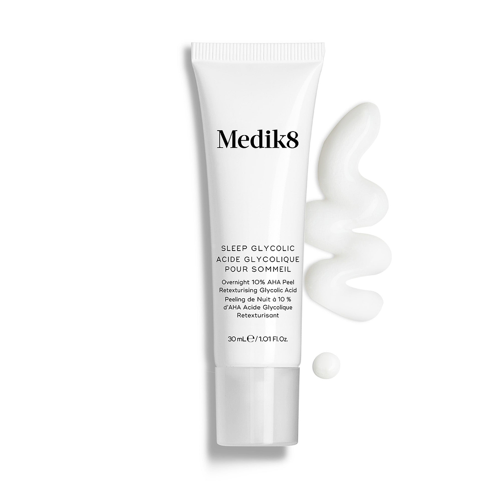 De tube van Medik8 Sleep Glycolic staat tegen een strakke witte achtergrond met een golvende veeg en een kleine druppel witte crèmetextuur. De tekst vermeldt dat het gaat om een 30 ml Time Release AHA Overnight At-Home Peel.