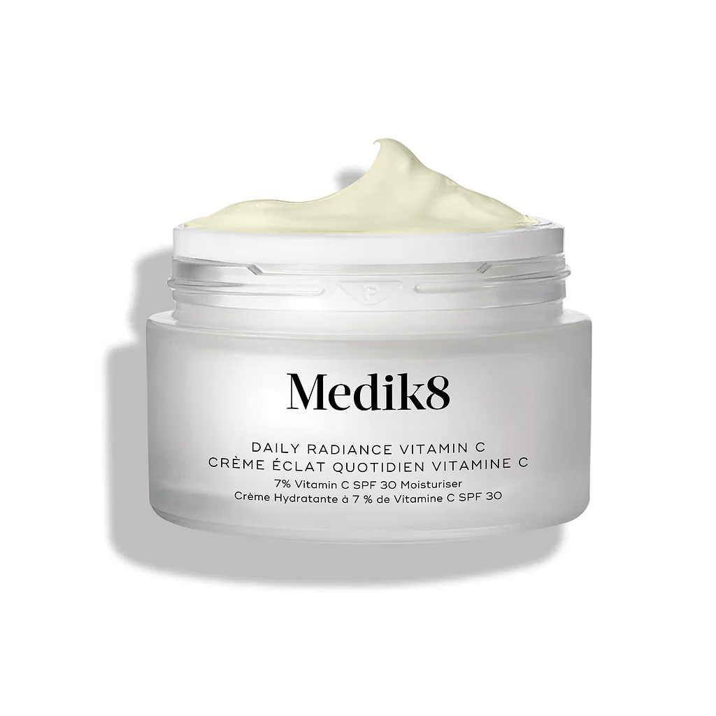 De glazen pot Medik8 Daily Radiance Vitamin C wordt geopend weergegeven met een royale toef lichtgele crème bovenop. De tekst vermeldt dat het product een 50 ml C-Tetra Cream SPF 30 Two-in-One Moisturiser is.