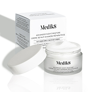 De pot Medik8 Advanced Night Restore staat geopend, met de witte deksel ertegenaan geleund en de productverpakking op de achtergrond. De afbeelding benadrukt de rijke textuur van de crème en het strakke, minimalistische ontwerp van de verpakking.