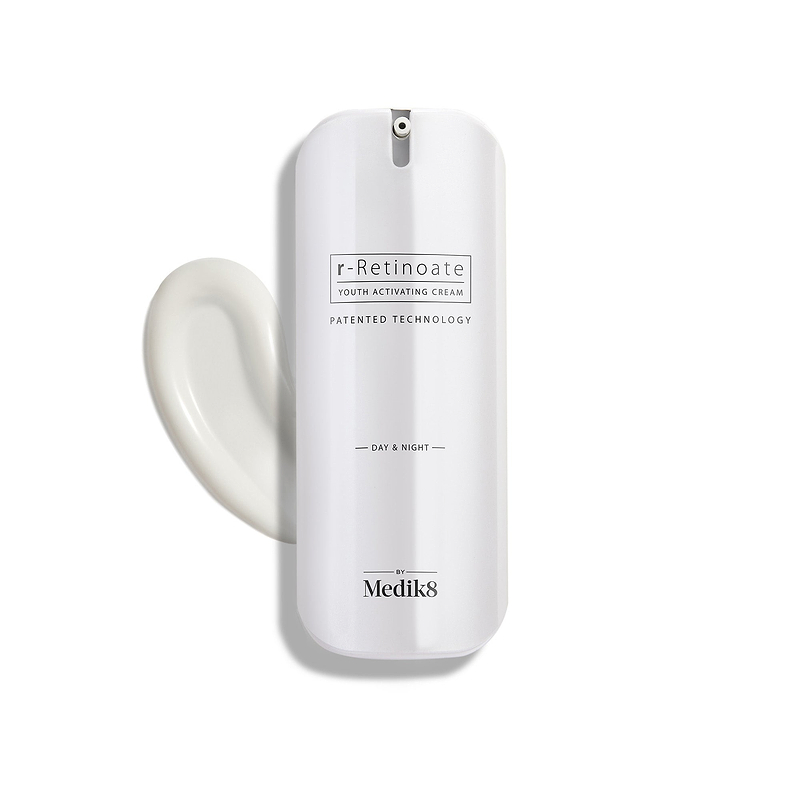 Biała butelka z pompką r-Retinoate Day & Night Eye Serum z kroplą produktu obok niej.
