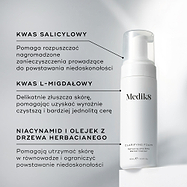 Butelka z pompką Medik8 Clarifying Foam stoi na białym bloku na czystym, szarym tle. Tekst podkreśla kluczowe składniki: kwas salicylowy rozkładający zanieczyszczenia powodujące niedoskonałości, kwas L-migdałowy zapewniający delikatne złuszczanie i bardziej wyrównaną cerę oraz niacynamid i olejek z drzewa herbacianego wspierające utrzymanie zrównoważonej, wolnej od niedoskonałości skóry.
