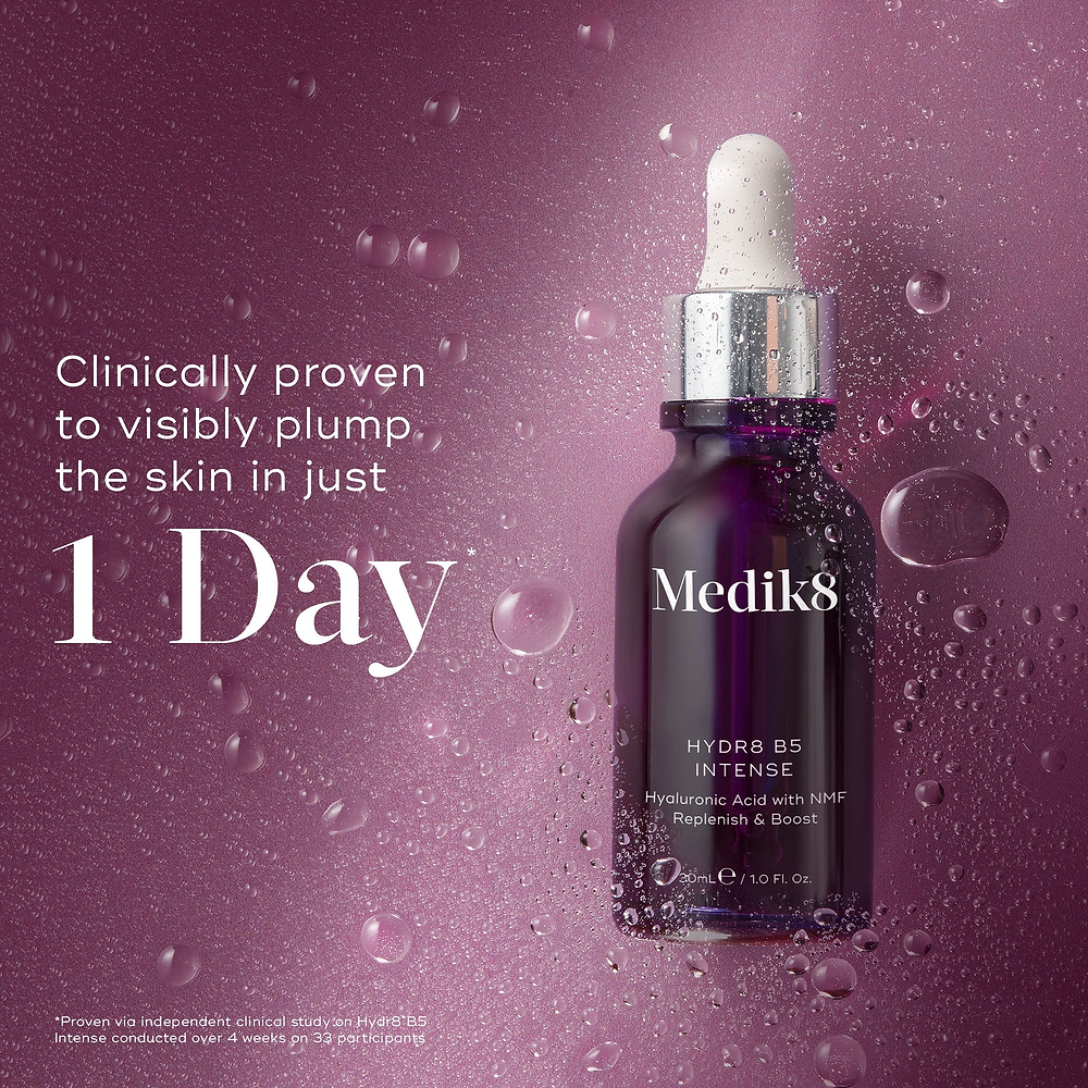 Medik8 Hydr8 B5 Intense glass dropper bottle centered on a shimmering purple background with translucent water droplets. Bold text states the product is clinically proven to visibly plump the skin in just 1 Day.