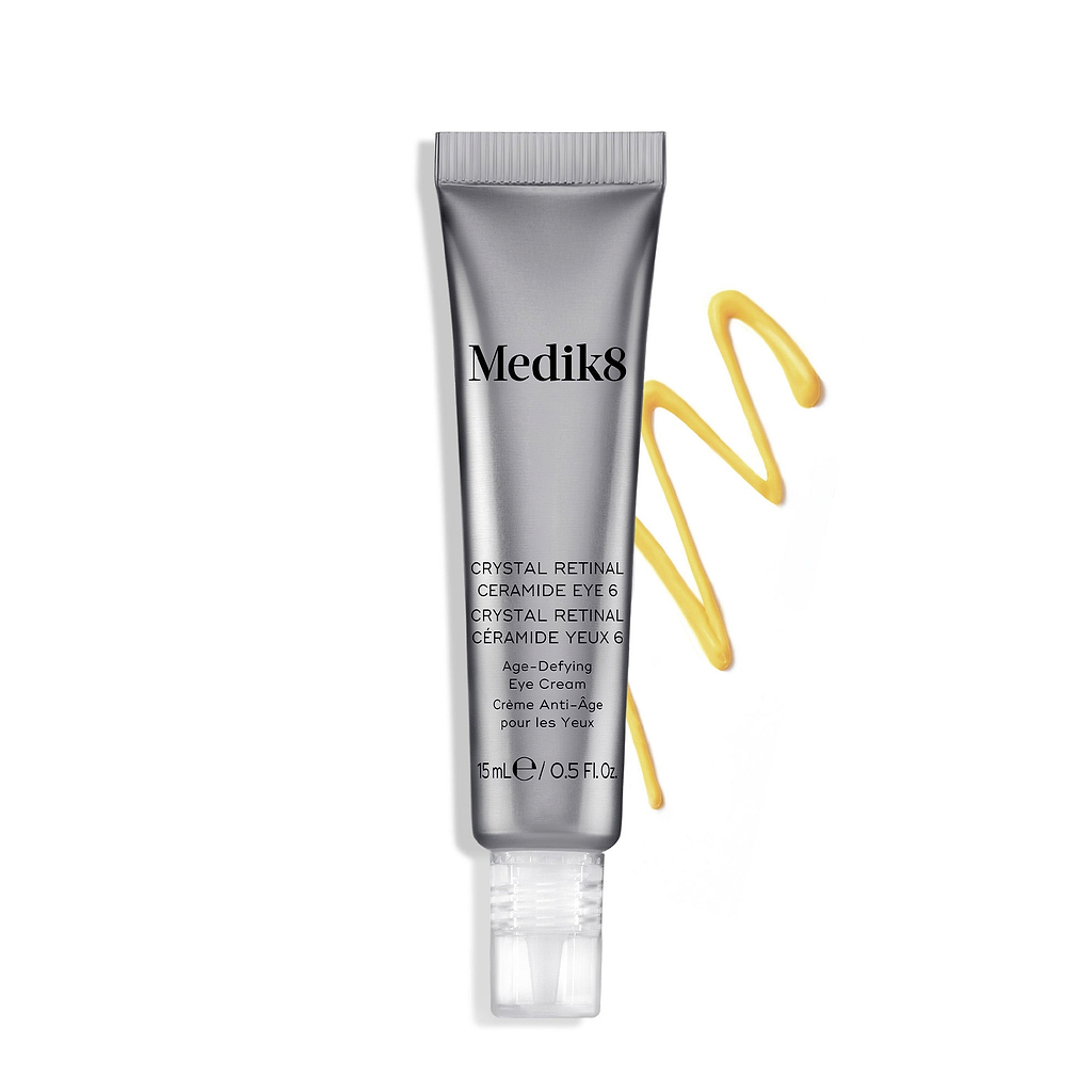 A silver tube of Crystal Retinal Ceramide Eye 6 stands upright, with a swirl of yellow-orange cream to its right.