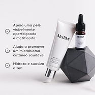 O tubo Balance Moisturiser e o frasco conta-gotas Glycolic Acid Activator estão apoiados num bloco geométrico escuro sobre um fundo branco. Os marcadores listam os benefícios: apoia uma pele visivelmente aperfeiçoada e matificada, ajuda a promover um microbioma cutâneo saudável, e hidrata e suaviza a tez.