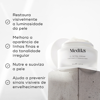 Um pote aberto de Medik8 C-Tetra Cream assenta num bloco de betão texturizado contra um fundo claro. O texto em português lista os benefícios: restaura visivelmente a luminosidade da pele, melhora a aparência de linhas finas e da tonalidade irregular, nutre e suaviza a pele e ajuda a prevenir sinais visíveis de envelhecimento.
