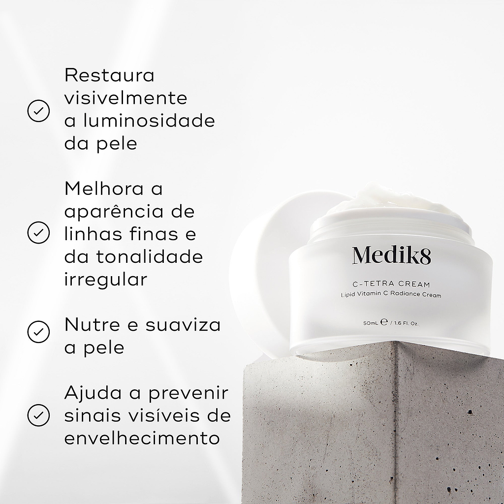 Um pote aberto de Medik8 C-Tetra Cream assenta num bloco de betão texturizado contra um fundo claro. O texto em português lista os benefícios: restaura visivelmente a luminosidade da pele, melhora a aparência de linhas finas e da tonalidade irregular, nutre e suaviza a pele e ajuda a prevenir sinais visíveis de envelhecimento.