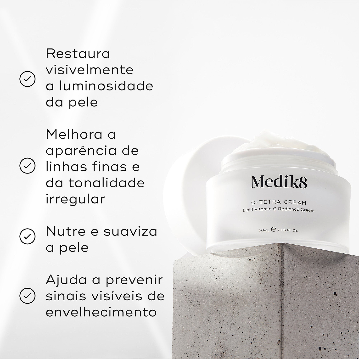 Um pote aberto de Medik8 C-Tetra Cream assenta num bloco de betão texturizado contra um fundo claro. O texto em português lista os benefícios: restaura visivelmente a luminosidade da pele, melhora a aparência de linhas finas e da tonalidade irregular, nutre e suaviza a pele e ajuda a prevenir sinais visíveis de envelhecimento.