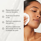 Primeiro plano de uma modella a aplicar um disco de algodão no rosto contra um fundo claro. O texto em português lista os benefícios: reequilibra o pH natural da pele, suaviza e acalma a tez, refina a aparência dos poros e auxilia a absorção de outros ativos de cuidado da pele.