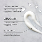 Close-up de um creme branco e gotas de líquido transparente num fundo de mármore claro. Linhas de texto destacam os ingredientes-chave: Ácido Glicólico para esfoliar, suavizar e ajudar a aperfeiçoar visivelmente a pele; Prebióticos e Pós-bióticos para ajudar a manter um microbioma cutâneo equilibrado; e Niacinamida para ajudar a equilibrar a produção de oleosidade.