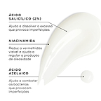 Close-up de uma amostra de gel transparente contra um fundo branco. Linhas de texto destacam os ingredientes-chave: Ácido Salicílico (2%) para ajudar a dissolver o excesso que provoca imperfeições, Niacinamida para reduzir a vermelhidão visível e ajudar a regular a produção de oleosidade, e Ácido Azelaico para ajudar a combater as bactérias que provocam imperfeições.