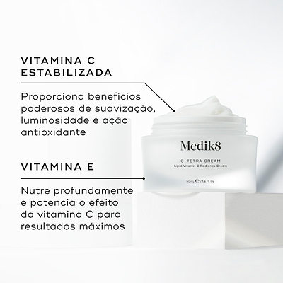 Um pote aberto de Medik8 C-Tetra Cream revelando o creme branco no interior, colocado sobre um bloco branco contra um fundo claro. O texto em português destaca os ingredientes principais: Vitamina C Estabilizada que proporciona benefícios poderosos de suavização, luminosidade e ação antioxidante, e Vitamina E que nutre profundamente e potencia o efeito da vitamina C para resultados máximos.