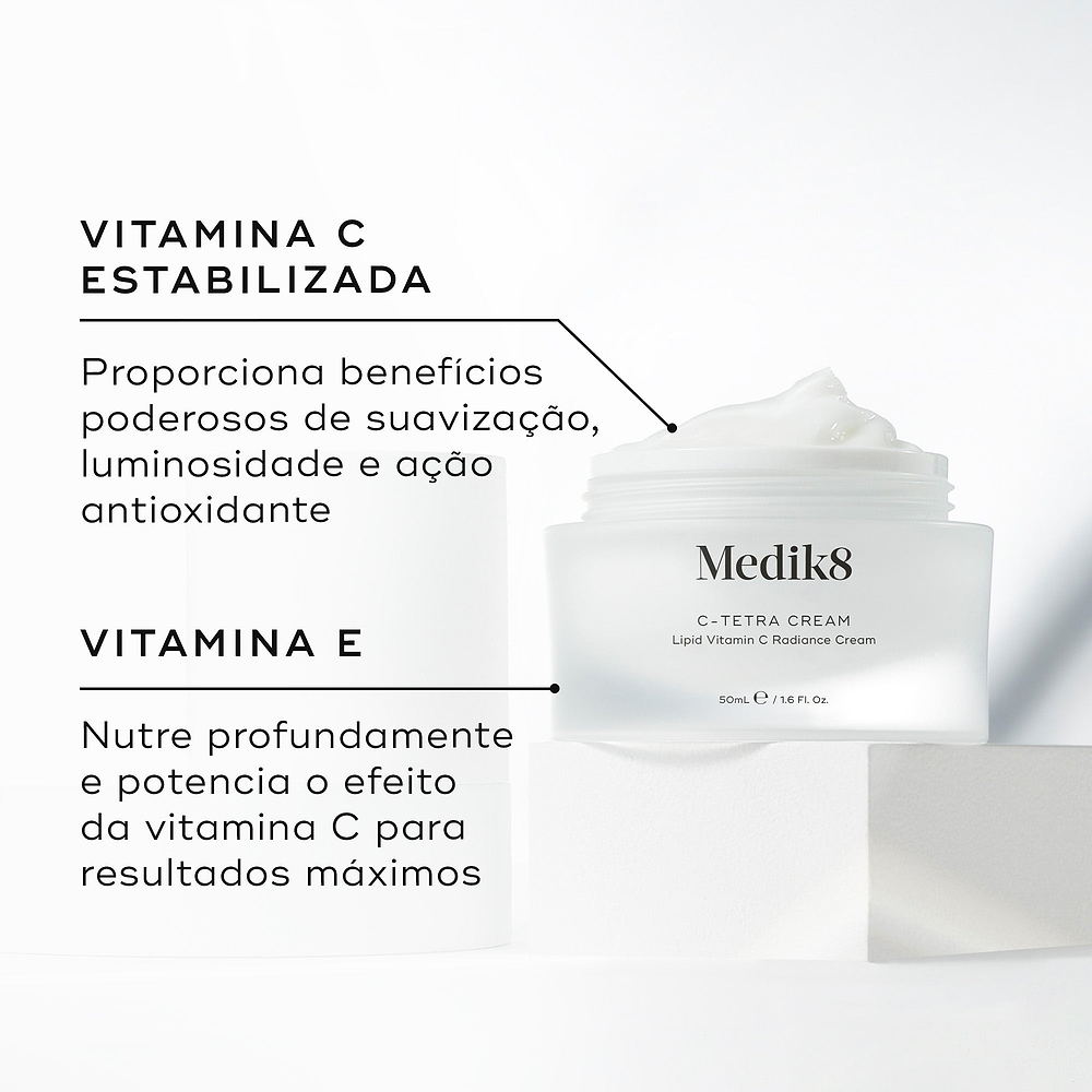 Um pote aberto de Medik8 C-Tetra Cream revelando o creme branco no interior, colocado sobre um bloco branco contra um fundo claro. O texto em português destaca os ingredientes principais: Vitamina C Estabilizada que proporciona benefícios poderosos de suavização, luminosidade e ação antioxidante, e Vitamina E que nutre profundamente e potencia o efeito da vitamina C para resultados máximos.