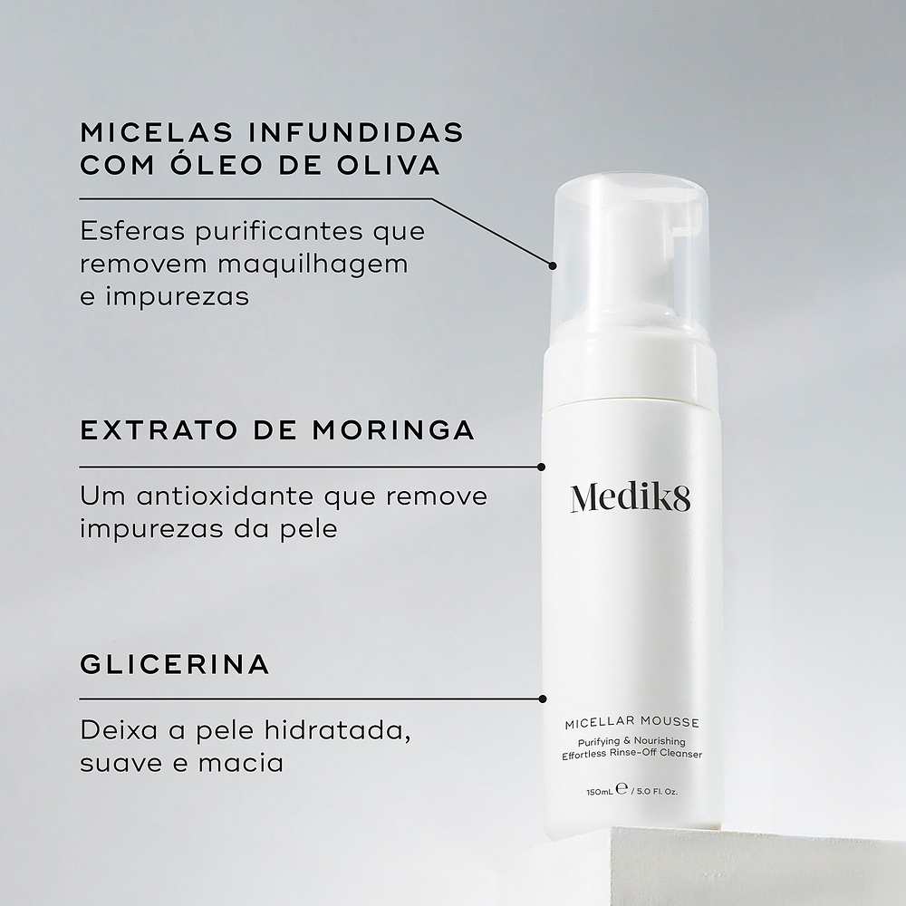 O frasco doseador Micellar Mousse assenta num pedestal branco contra um fundo cinza claro. Linhas de texto destacam os ingredientes-chave: Micelas Infundidas com Óleo de Oliva para remover maquilhagem e impurezas, Extrato de Moringa para remover impurezas da pele, e Glicerina para deixar a pele hidratada e macia.