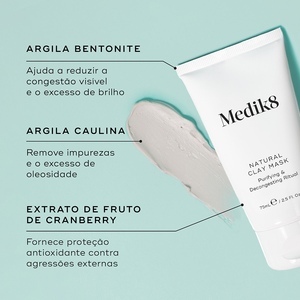 Close-up de uma textura de argila cinza e do tubo Natural Clay Mask contra um fundo verde menta claro. Linhas de texto destacam os ingredientes-chave: Argila Bentonite para ajudar a reduzir a congestão visível e o excesso de brilho, Argila Caulina para remover impurezas e o excesso de oleosidade, e Extrato de Fruto de Cranberry para fornecer proteção antioxidante contra agressões externas.