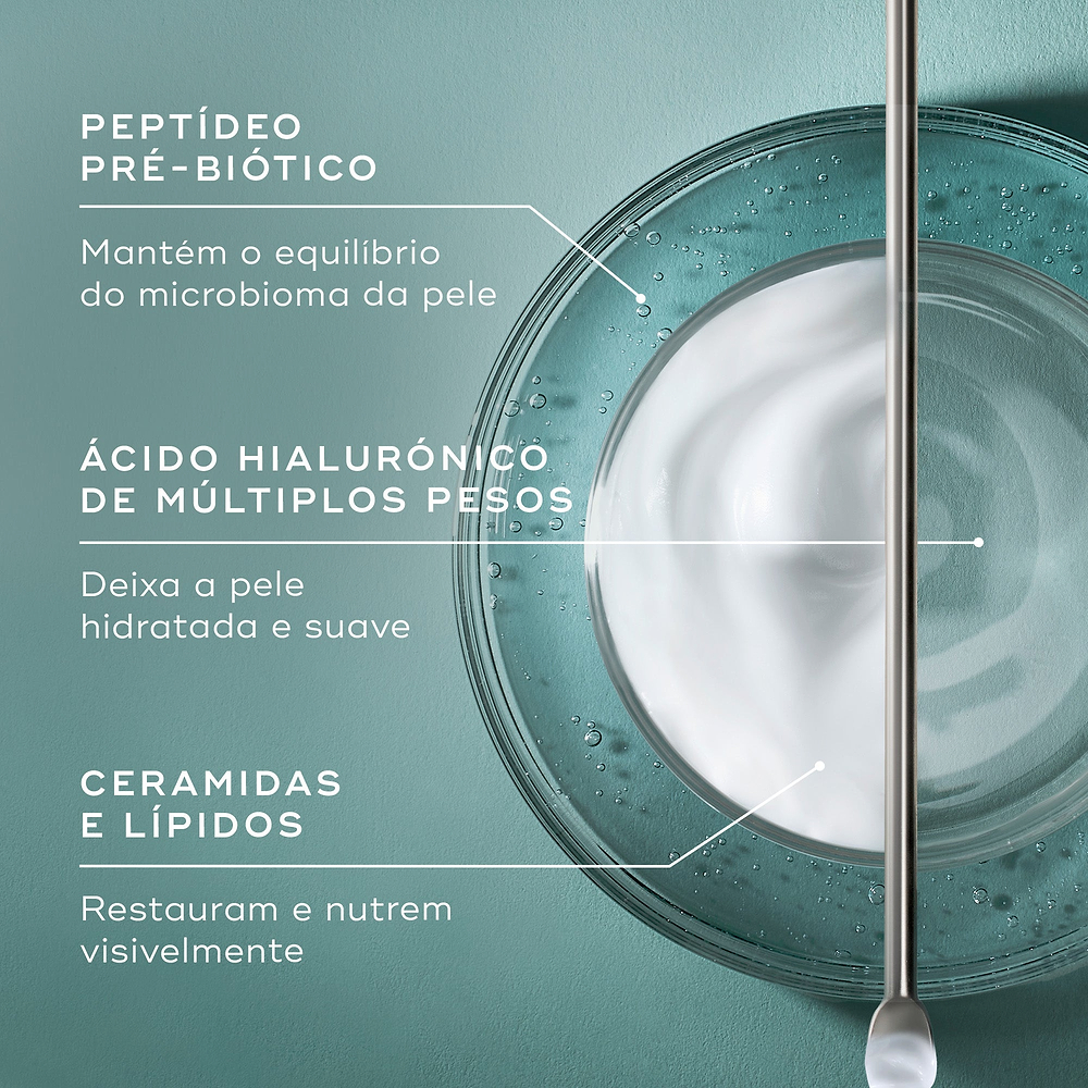 Uma vista superior de um creme branco numa placa de Petri sobre um fundo verde-azulado. Linhas de texto apontam para o creme, listando os ingredientes-chave: Peptídeo Pré-biótico para manter o equilíbrio do microbioma, Ácido Hialurónico de múltiplos pesos para deixar a pele hidratada e suave, e Ceramidas e Lípidos para restaurar e nutrir visivelmente.