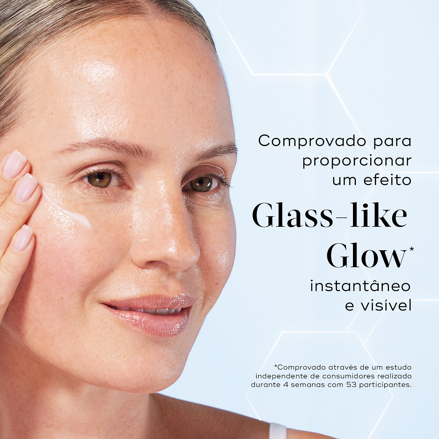Primeiro plano de uma modella sorridente a aplicar uma porção de sérum branco na bochecha contra um fundo azul claro com gráficos hexagonais subtis. O texto em português destaca que o produto é comprovado para proporcionar um efeito Glass-like Glow instantâneo e visível.