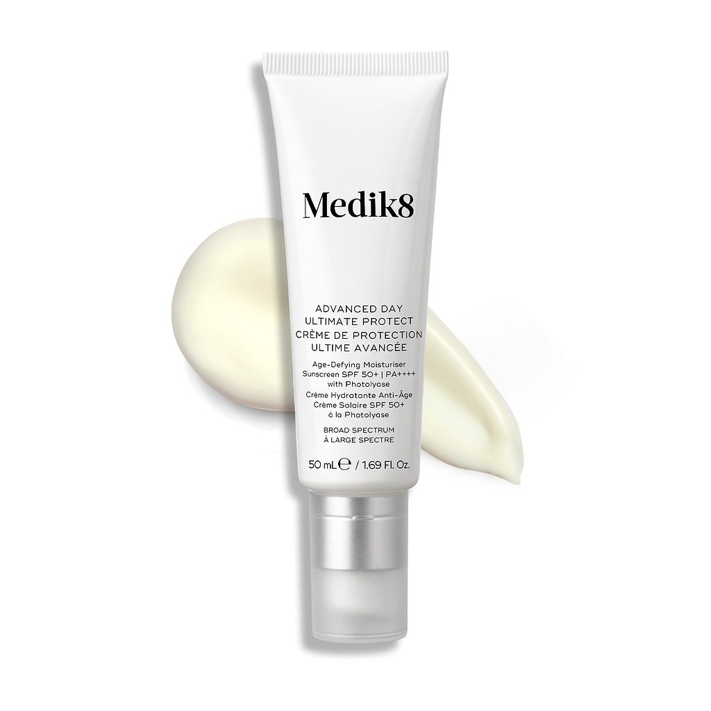 Um tubo branco de Medik8 Advanced Day Ultimate Protect está colocado na vertical, com uma camada de creme de cor clara ao lado.