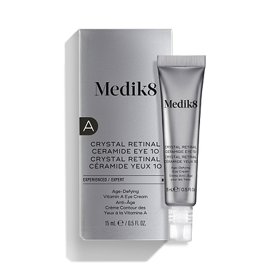 Uma bisnaga prateada do Medik8 Crystal Retinal Ceramide Eye 10 está colocada ao lado da sua embalagem prateada correspondente.