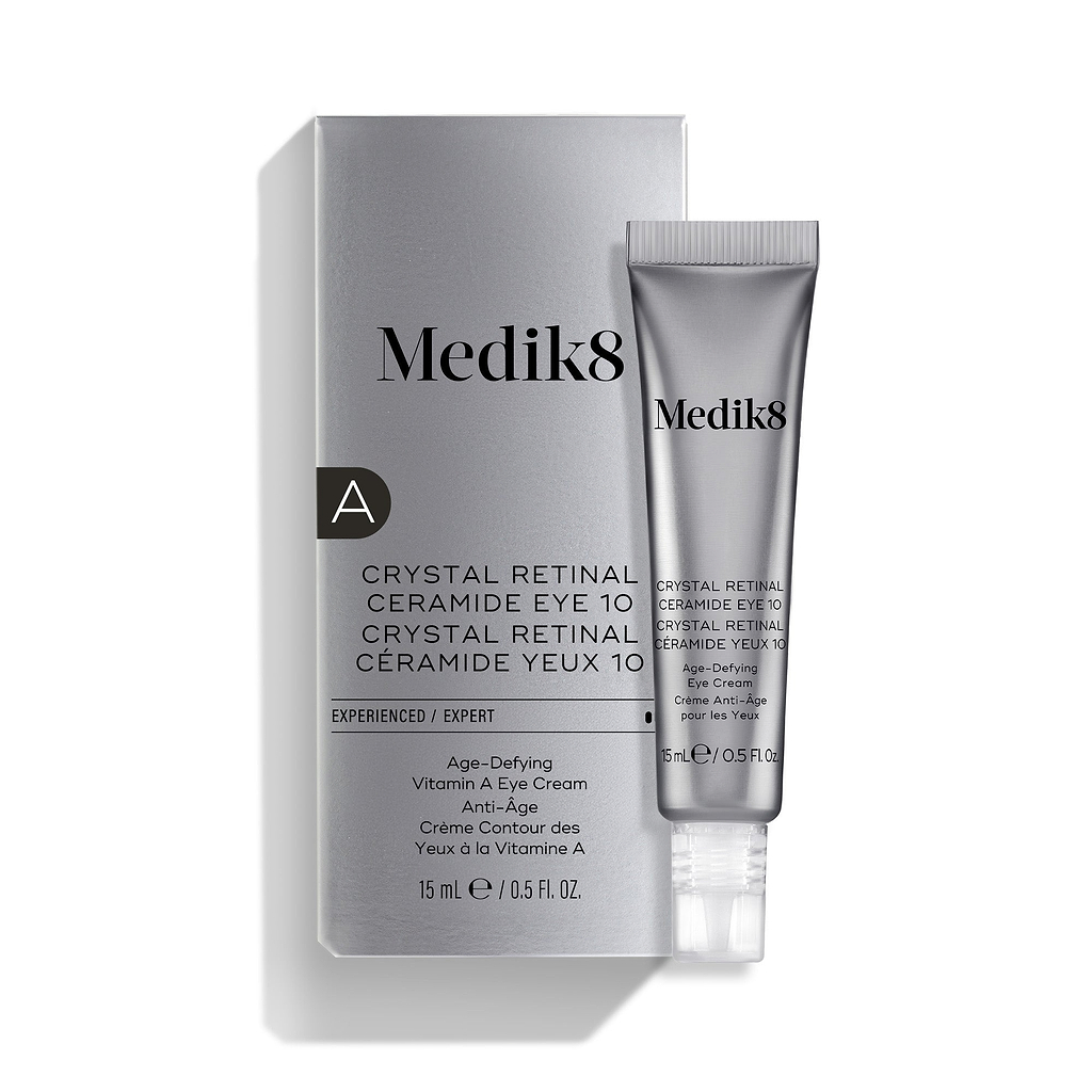 Uma bisnaga prateada do Medik8 Crystal Retinal Ceramide Eye 10 está colocada ao lado da sua embalagem prateada correspondente.