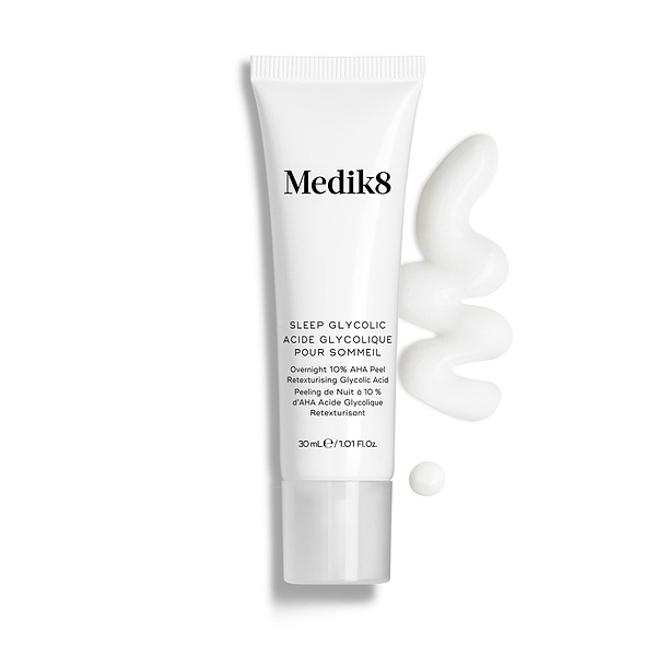 Bisnaga do Medik8 Sleep Glycolic apresentada sobre um fundo branco limpo, com uma camada ondulada e uma pequena gota de creme branco, destacando a sua textura.
