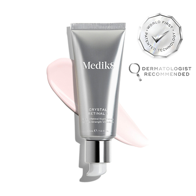 O tubo do sérum Medik8 Crystal Retinal 1 é exibido sobre um fundo branco limpo com uma grande amostra de creme pêssego. Selos prateados à direita destacam "Tecnologia Patenteada Pioneira no Mundo" e "Recomendado por Dermatologistas". O texto no tubo identifica-o como um sérum noturno de retinal estável com vitamina A de força suave.
