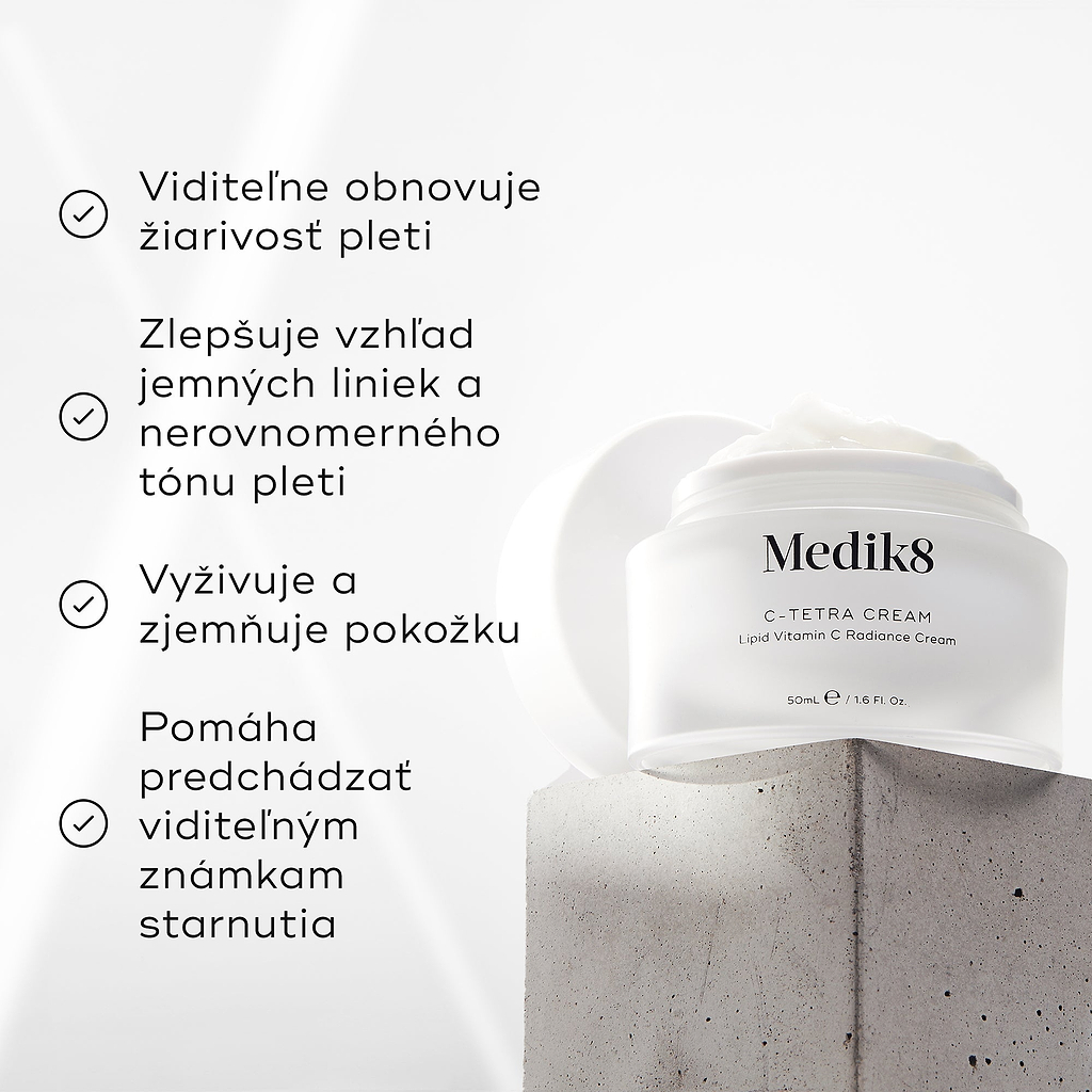 Kelímok krému Medik8 C-Tetra na sivom kamennom bloku na bielom pozadí s jemnými lúčmi svetla. Obrázok obsahuje štyri zaškrtnuté tvrdenia: viditeľne obnovuje rozjasnenie pleti, zlepšuje vzhľad jemných línií a nejednotného tónu pleti, vyživuje a zjemňuje pokožku a pomáha predchádzať viditeľným známkam starnutia.
