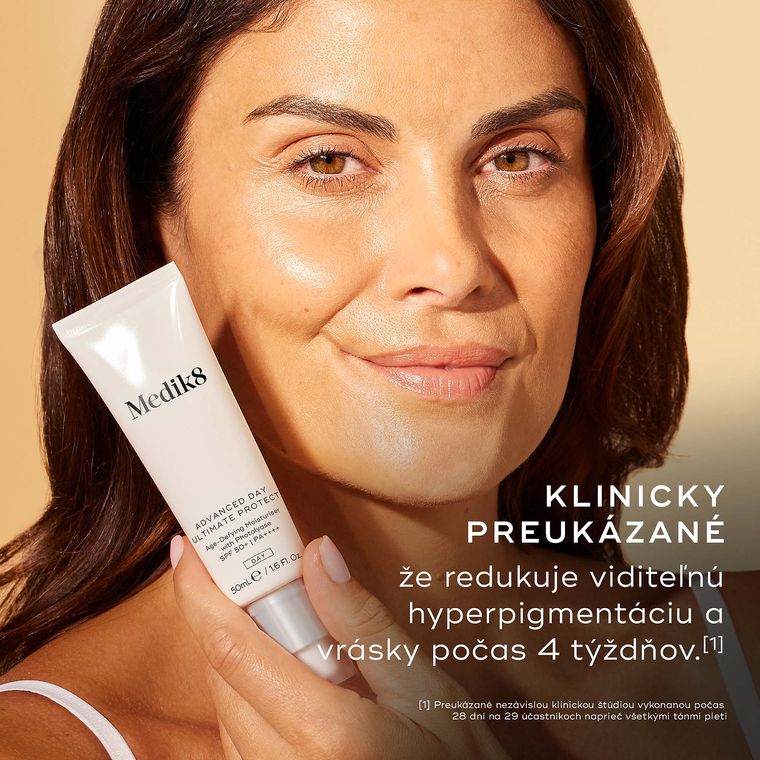 Detail usmievajúcej sa ženy, ktorá drží vedľa tváre tubu krému Medik8 Advanced Day Ultimate Protect. Text uvádza: „KLINICKY PREUKÁZANÉ: znižuje viditeľnosť pigmentových škvŕn a vrások za 4 týždne“.
