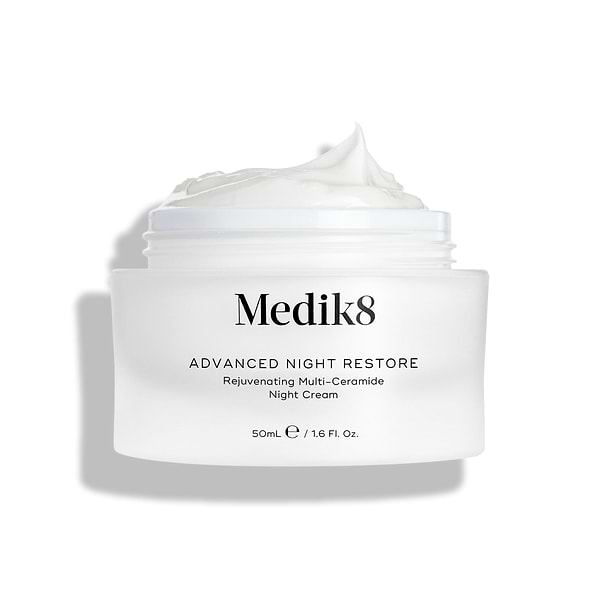 Medik8 Advanced Night Restore cream jar shown open with a rich dollop of white cream peaked on top against a clean white background, highlighting its smooth, restorative texture. Black text on the jar reads "Rejuvenating Multi-Ceramide Night Cream".