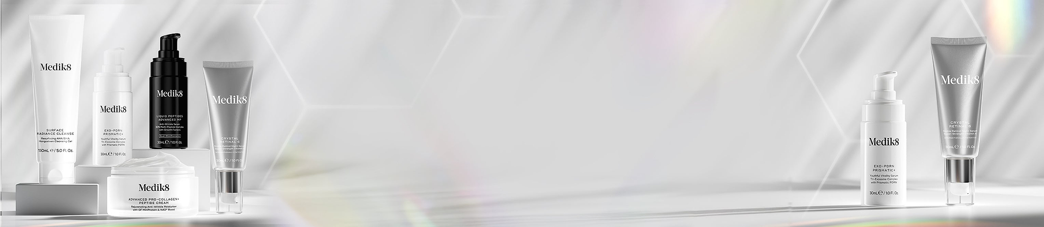 Set of skincare serums on a white surface with a hexagonal background