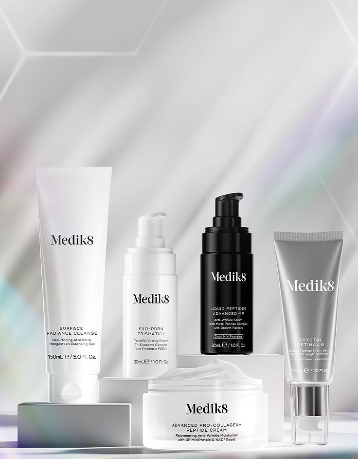 Set of skincare serums on a white surface with a hexagonal background