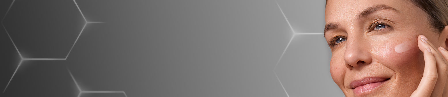 A professional web banner for the Medik8 regime builder. On the left, a dark grey gradient background with a subtle white hexagonal pattern. On the right, a close-up of a woman with glowing skin applying a cream to her cheek. Central white text reads 'Build Your Tailored Skincare Regime' with a call-to-action button labelled 'BUILD MY REGIME'.