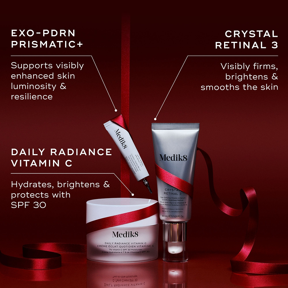 Three Medik8 products wrapped in a red ribbon against a deep red background, with text highlighting key benefits for each. The Exo-PDRN Prismatic+ deluxe sample "Supports visibly enhanced skin luminosity & resilience," the Daily Radiance Vitamin C jar "Hydrates, brightens & protects with SPF 30," and the Crystal Retinal 3 tube "Visibly firms, brightens & smooths the skin."