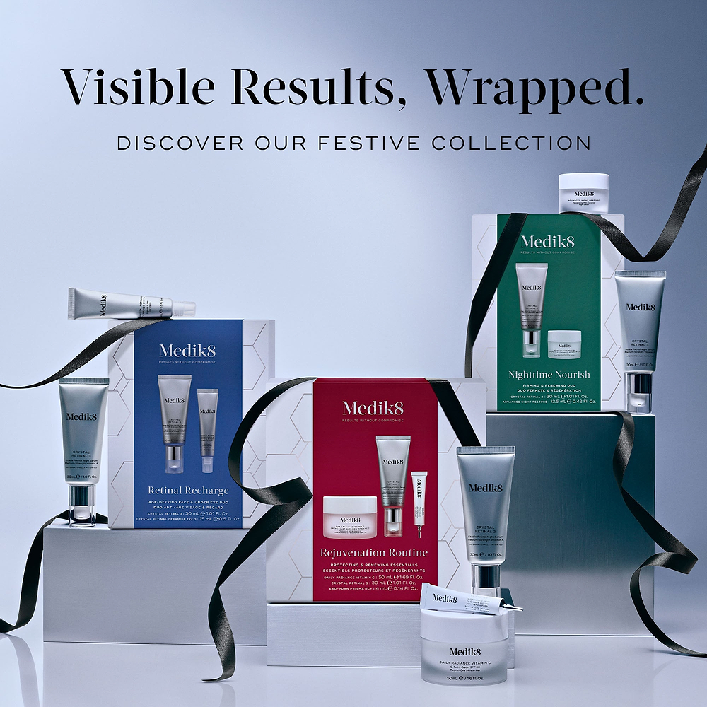 A display of three Medik8 festive gift boxes adorned with black ribbons against a light grey background, titled "Visible Results, Wrapped. Discover Our Festive Collection." It features the blue Retinal Recharge box with two tubes, the red Rejuvenation Routine box with a cream jar, tube, and pump bottle, and the green Nighttime Nourish box with a tube and cream jar.